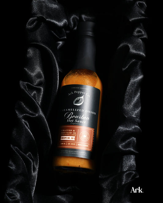 Small batch Caramelized Onion Bourbon Hot Sauce in rustic food styling setting