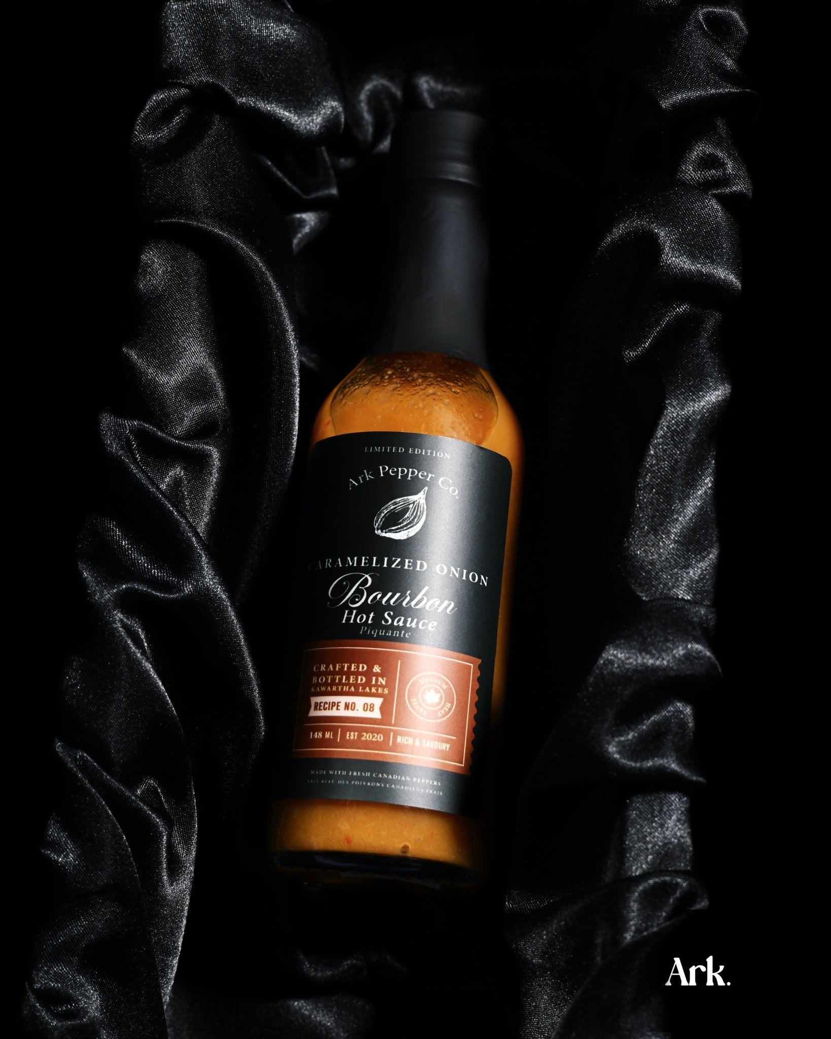 Small batch Caramelized Onion Bourbon Hot Sauce in rustic food styling setting